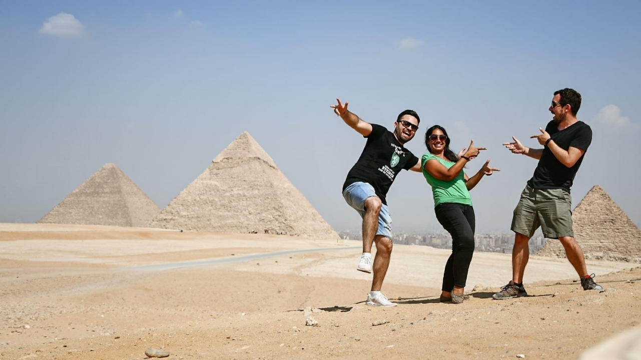 Groupe posant avec énergie devant les pyramides.