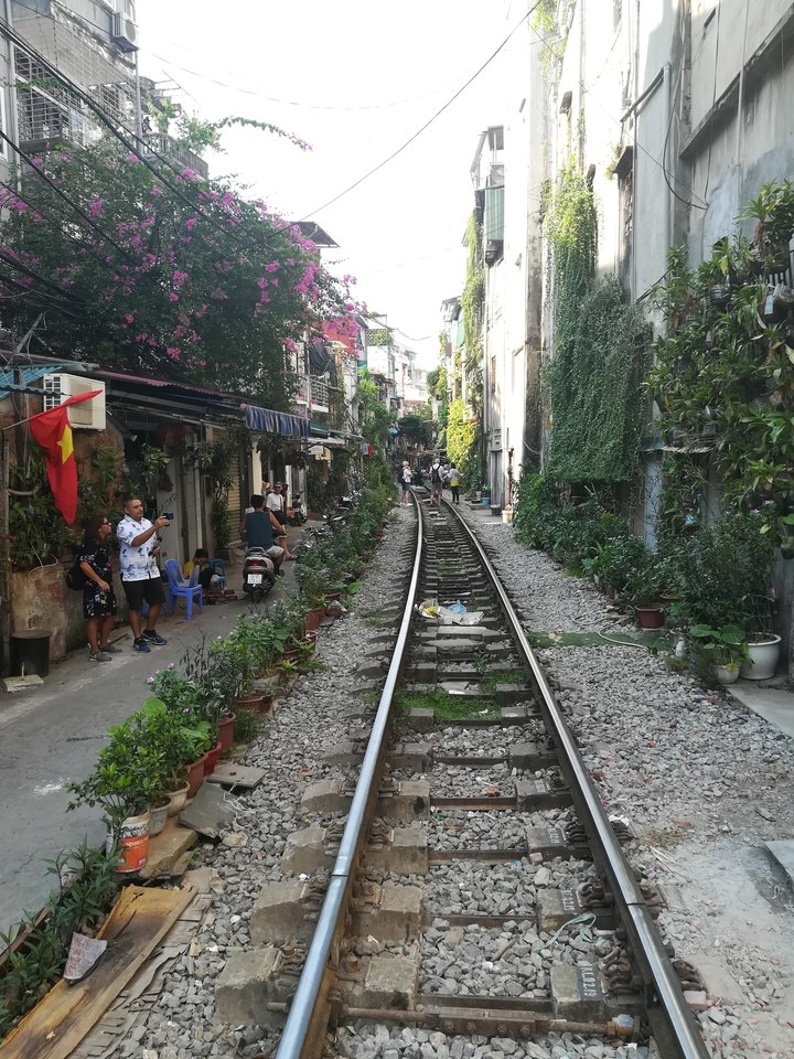 Voie ferrée traversant une ruelle étroite avec des gens.