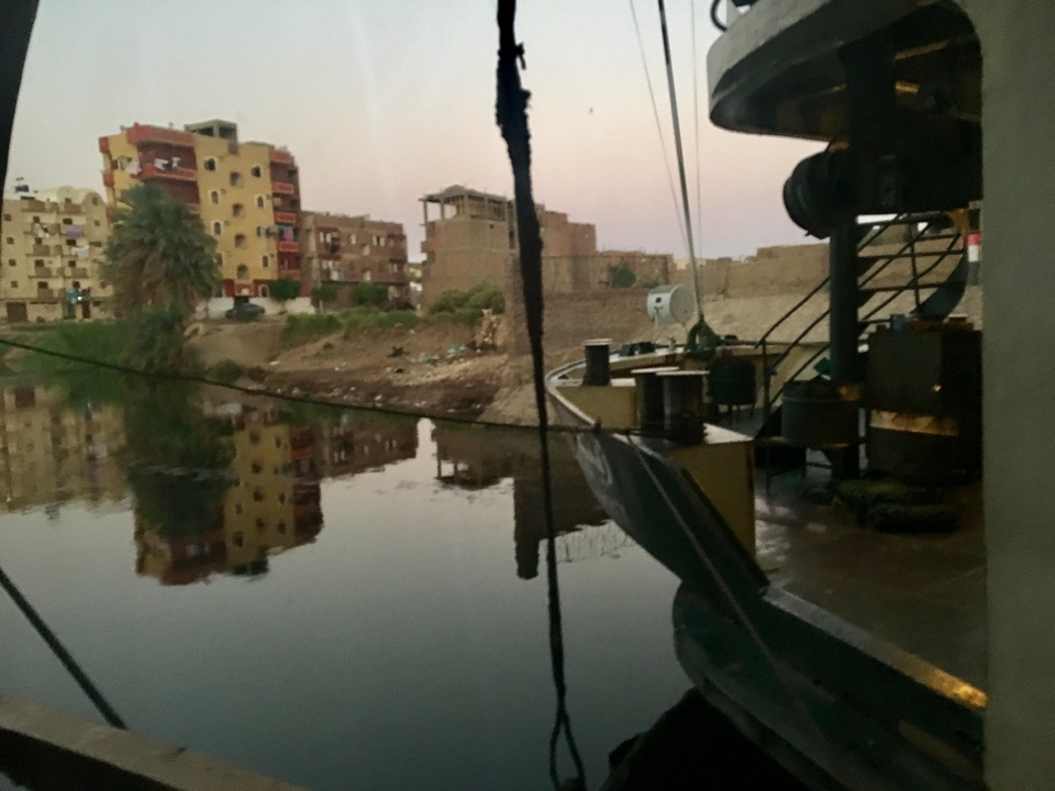 Vue au bord de l'eau faiblement éclairée avec des bâtiments sur la rive.