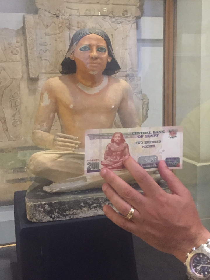 Gros plan de la monnaie égyptienne tenue par une statue.