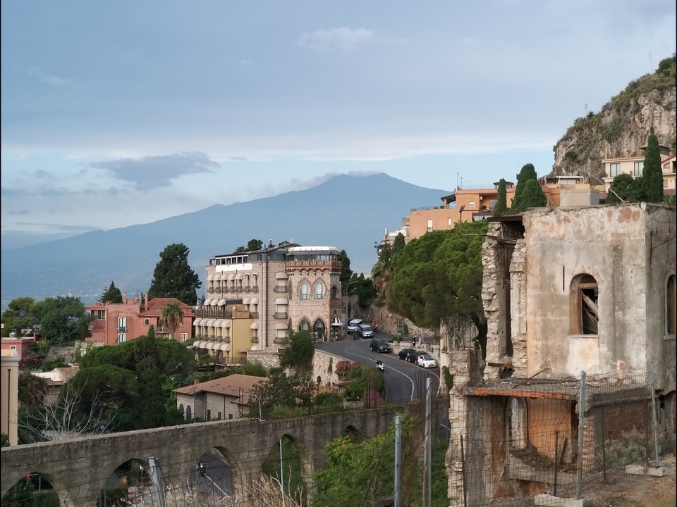 Vue panoramique d'une ville avec l'Etna en arrière-plan.