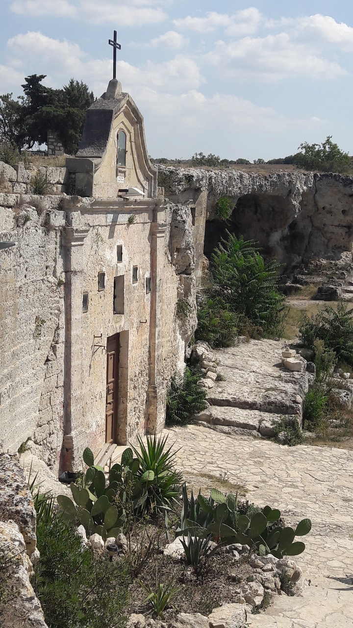 Bâtiment en pierre partiellement conservé dans un paysage rocheux.