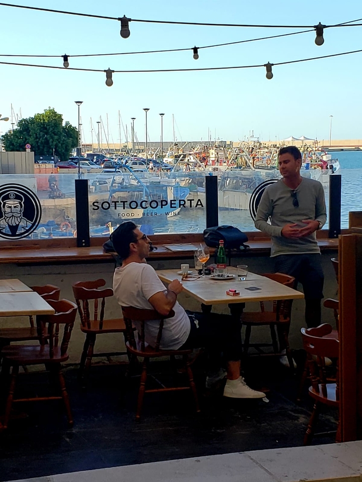 Deux personnes ayant une conversation dans un restaurant près du port.