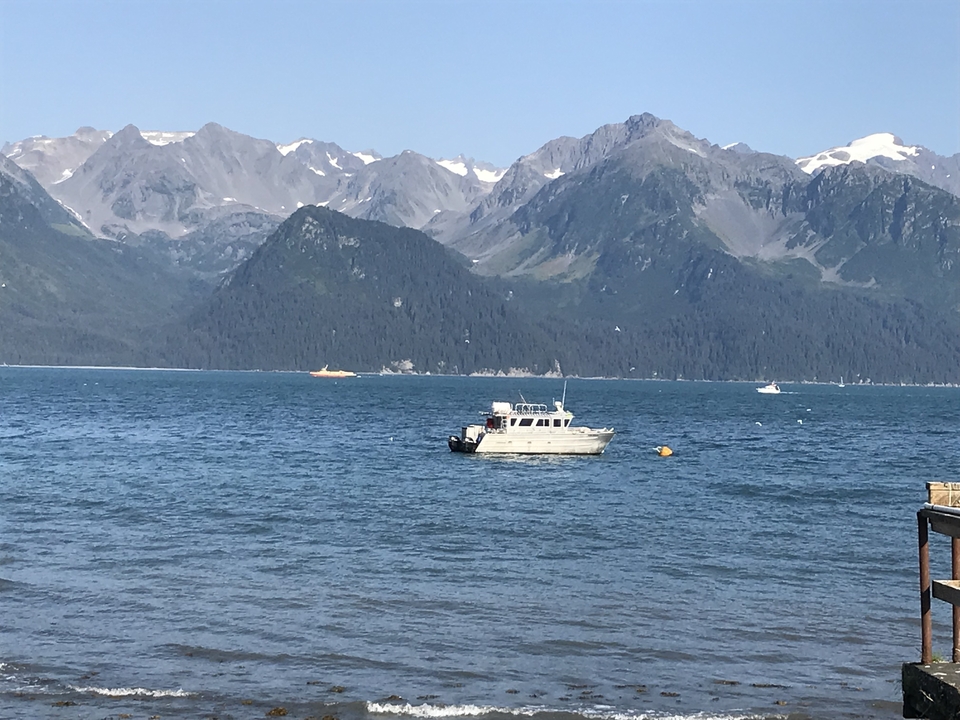 Bateau flottant sur l'eau avec une chaîne de montagnes en arrière-plan.