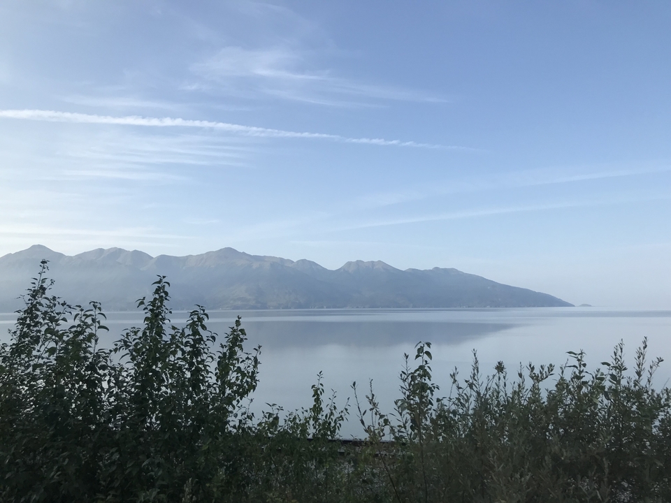 Vue sur le lac entourée de montagnes sous un ciel dégagé.