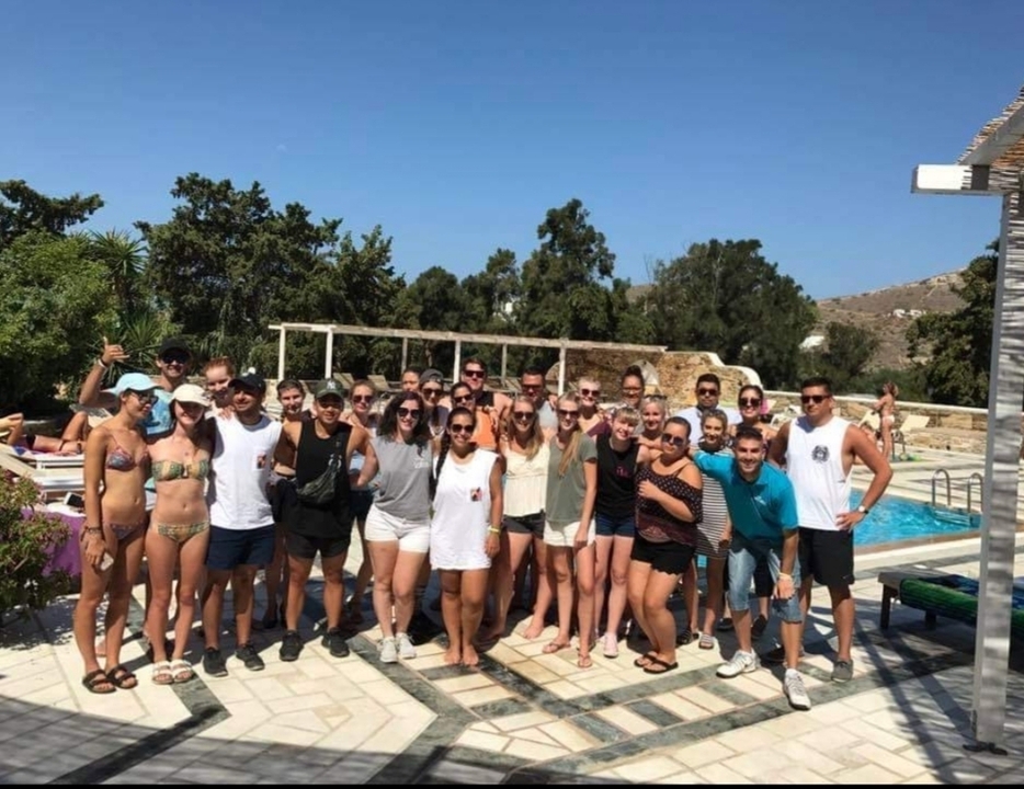 Group posing by a poolside under blue skies.