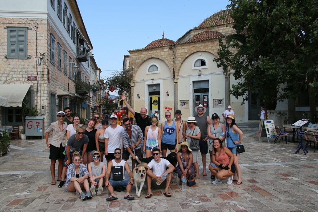 A large group of people posing in front of a building with domes.