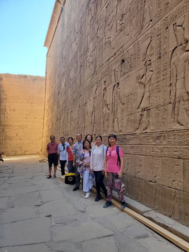 Un groupe de personnes posant près d'un mur avec des hiéroglyphes.
