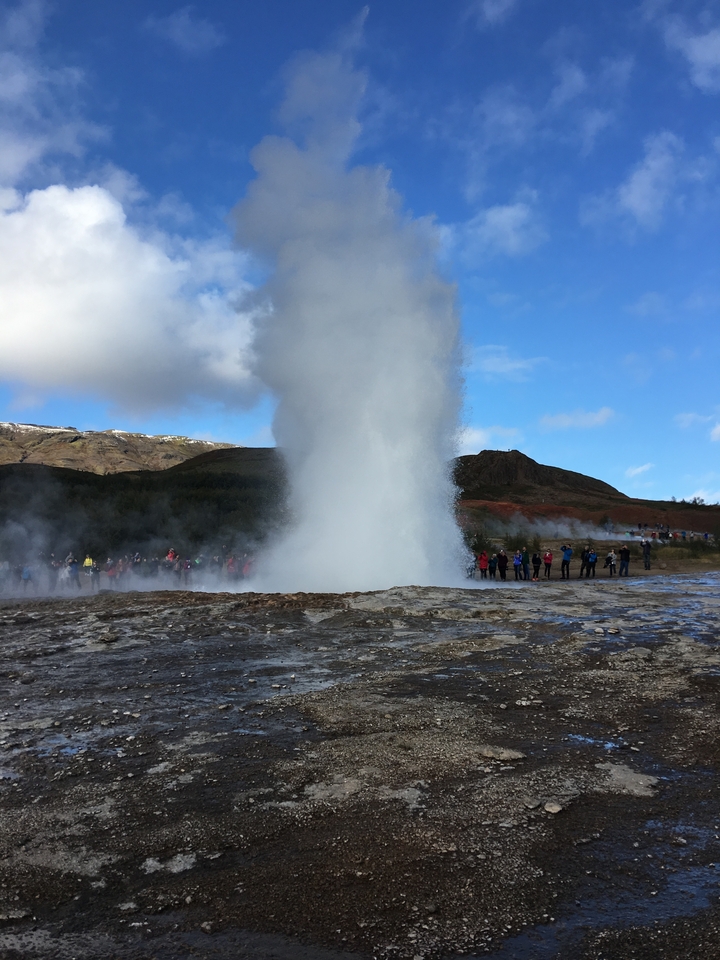 Éruption de geyser avec un groupe de personnes qui regardent en arrière-plan.
