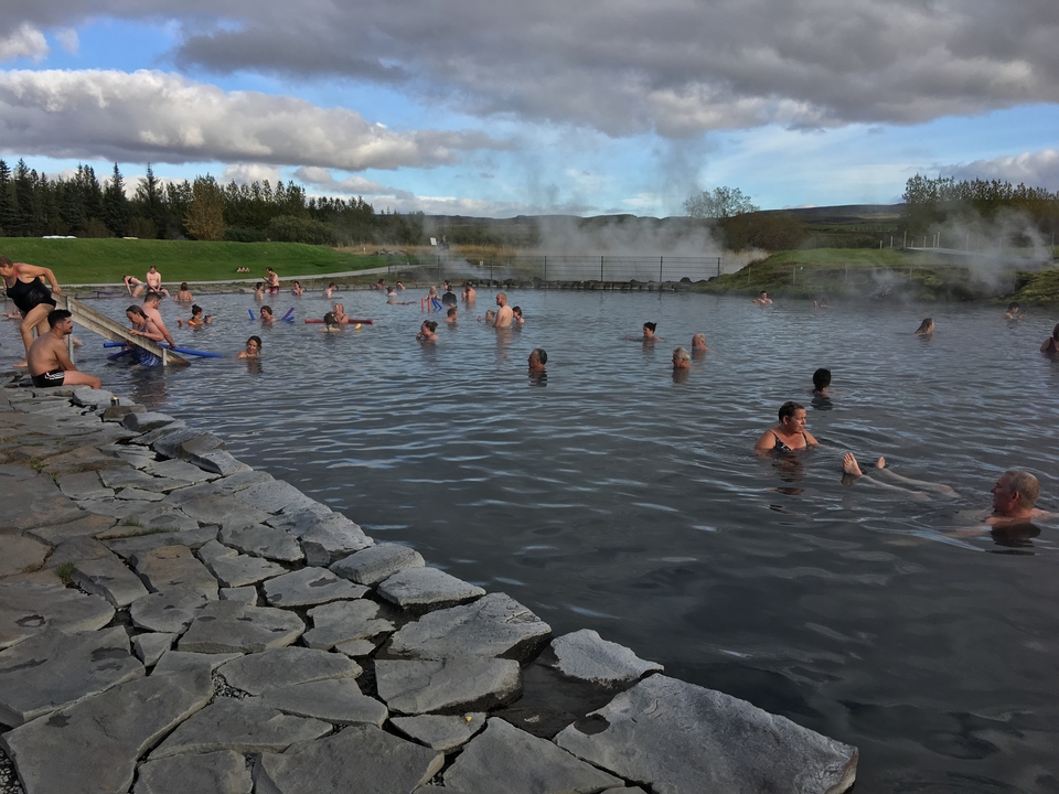 Des gens profitant d'un bassin de source chaude avec de la vapeur qui s'élève.