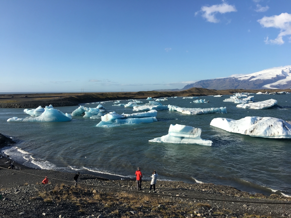 Lac glaciaire avec des icebergs éparpillés sous un ciel lumineux.