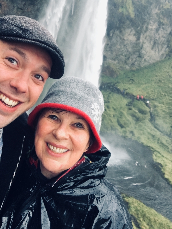 Deux personnes souriant à la caméra avec une cascade en arrière-plan.