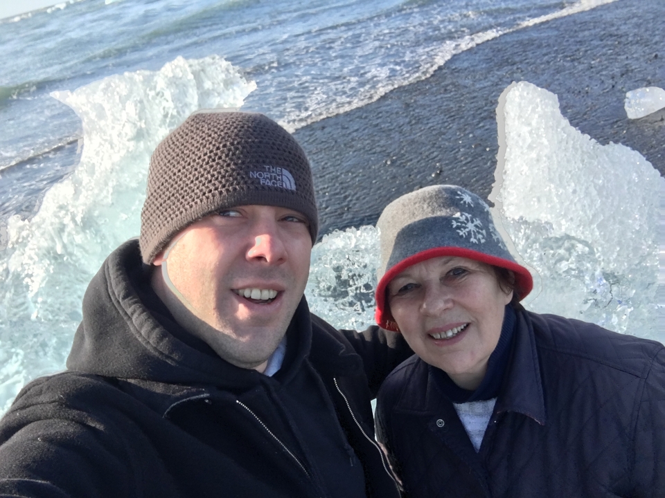 Deux personnes prenant un selfie près de formations de glace sur une plage.