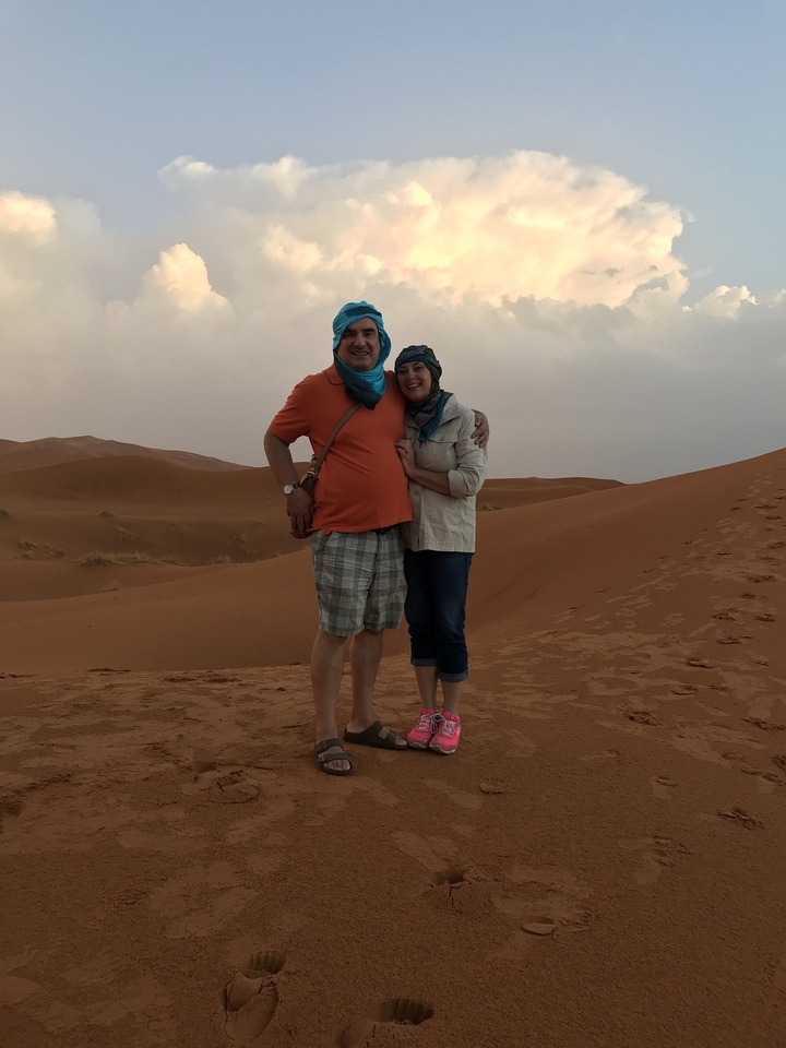 Couple posant dans un paysage désertique avec des dunes de sable.