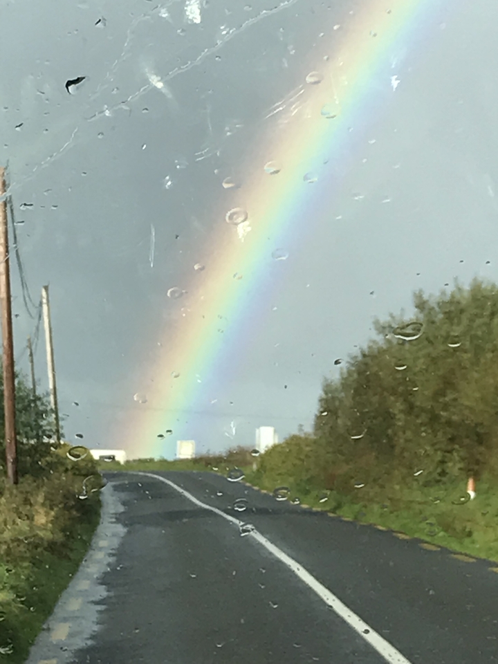Arc-en-ciel dans le ciel vu à travers une fenêtre avec des gouttes de pluie.
