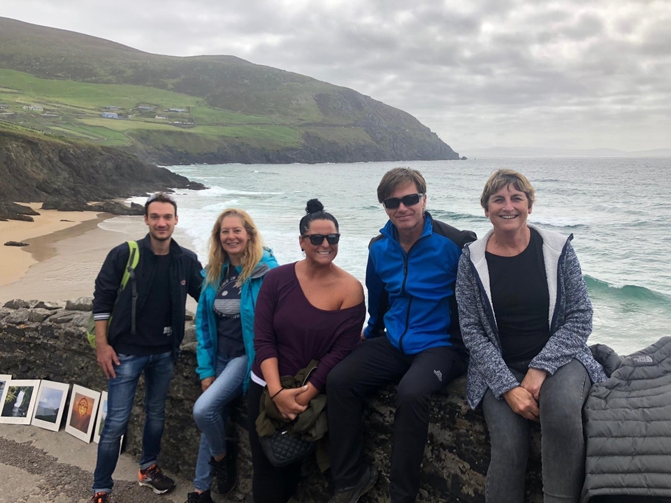 Groupe de personnes assises au bord de la mer avec des falaises.