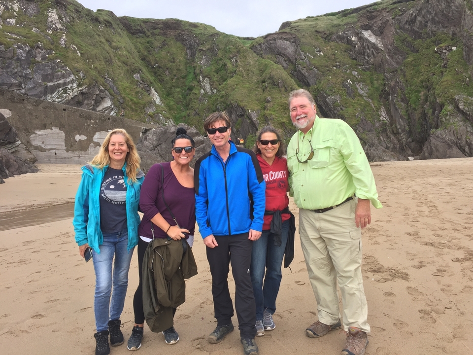 Groupe de personnes posant sur une plage avec des falaises en arrière-plan.
