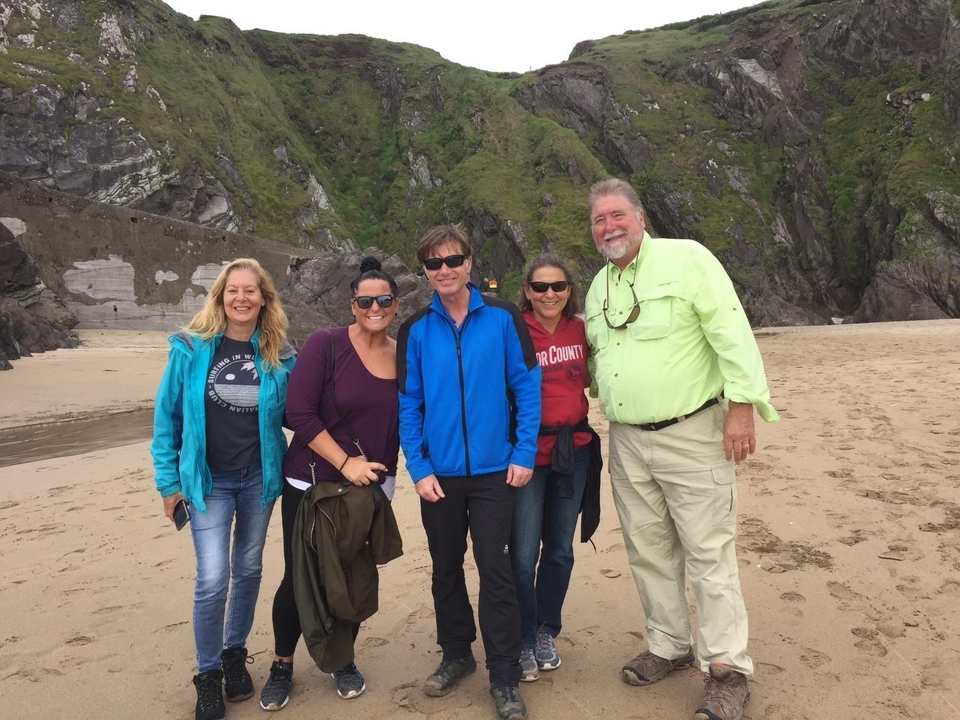 Groupe de personnes posant sur une plage avec des falaises en arrière-plan.