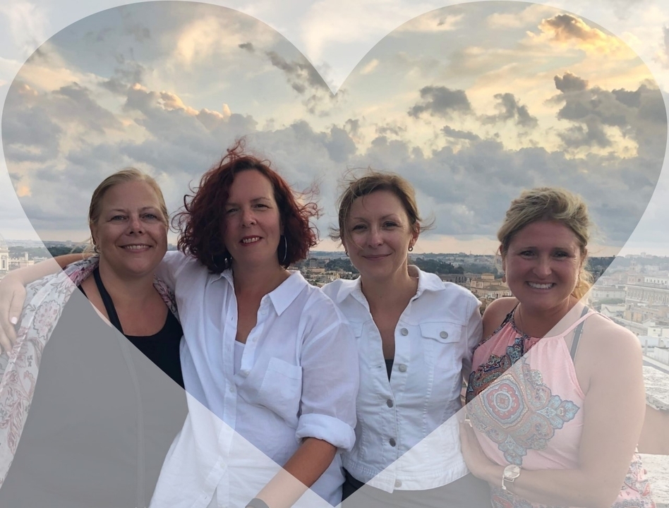 Quatre femmes posent avec un paysage urbain en arrière-plan.