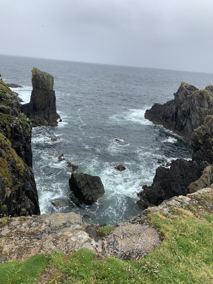 Falaises rocheuses côtières avec des vagues qui se brisent contre elles.