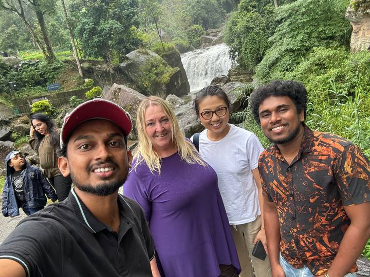 Groupe de personnes posant à côté d'une cascade.
