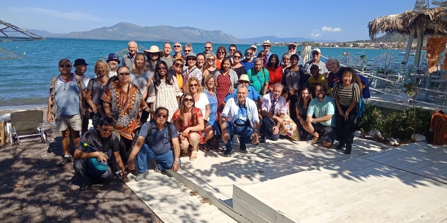 Photo de groupe au bord de la mer avec des collines au loin.