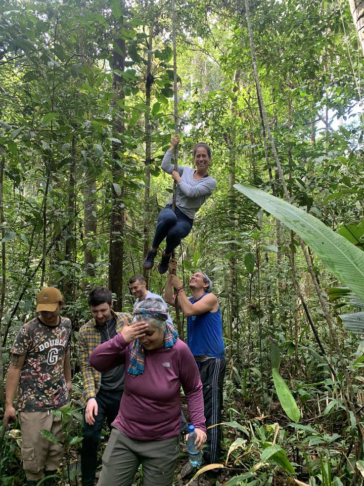 Groupe de personnes profitant de la jungle pendant qu'une personne se balance sur une liane.