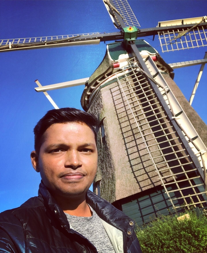 Personne prenant un selfie devant un moulin à vent par une journée claire.