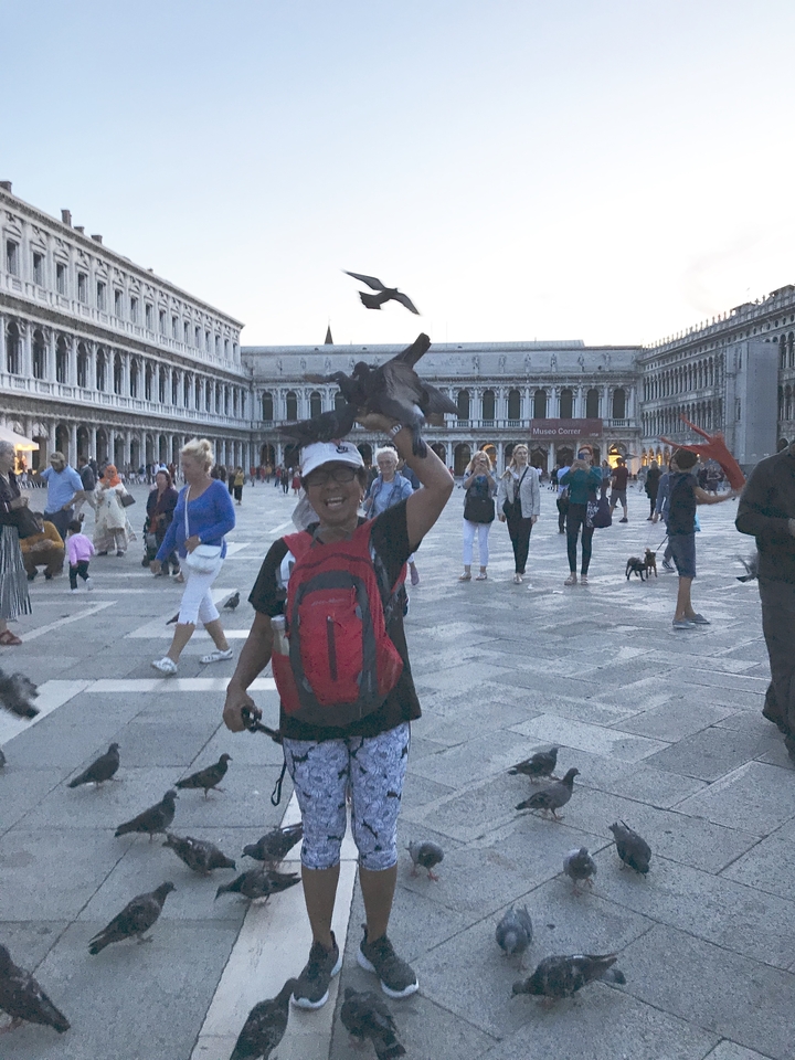 Personne avec un oiseau perché sur sa tête sur la place Saint-Marc de Venise.