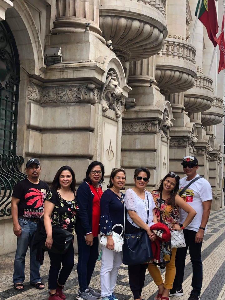 Des touristes prenant la pose devant la façade ornementée d'un bâtiment sculpté.