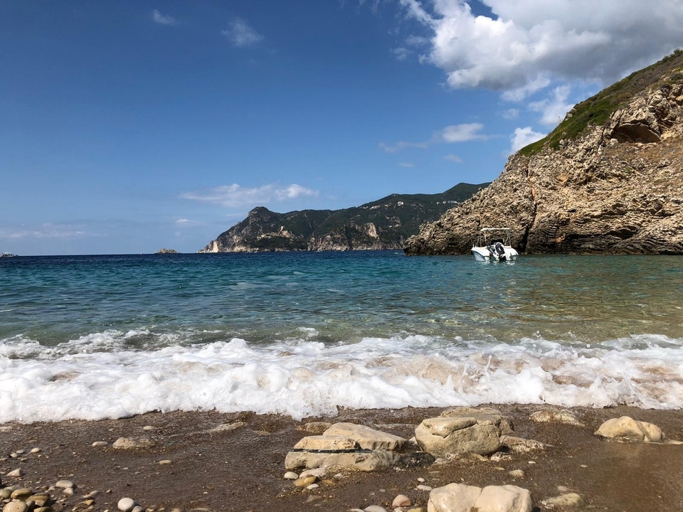 Vue idyllique de plage avec une eau bleue claire et des collines au loin.