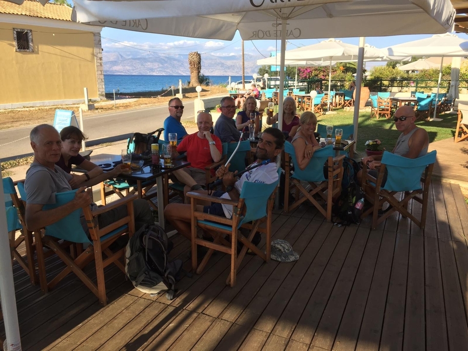 Un groupe de personnes savourant des boissons dans un café côtier avec vue sur la mer.