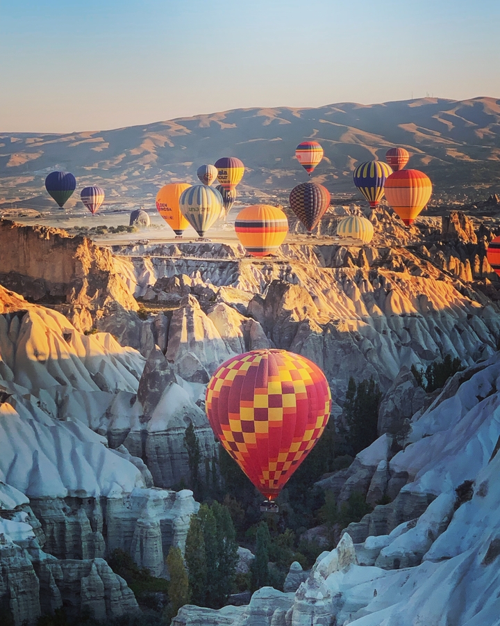 Montgolfières aux couleurs vives flottant au-dessus de formations rocheuses uniques.
