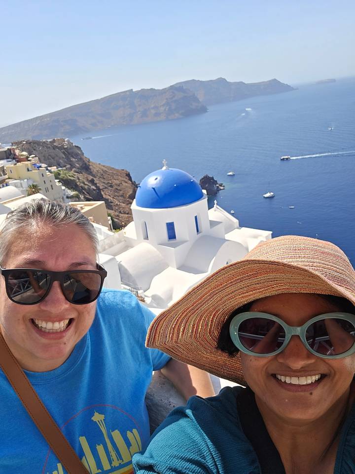 Deux personnes prenant un selfie avec une vue panoramique sur la côte.
