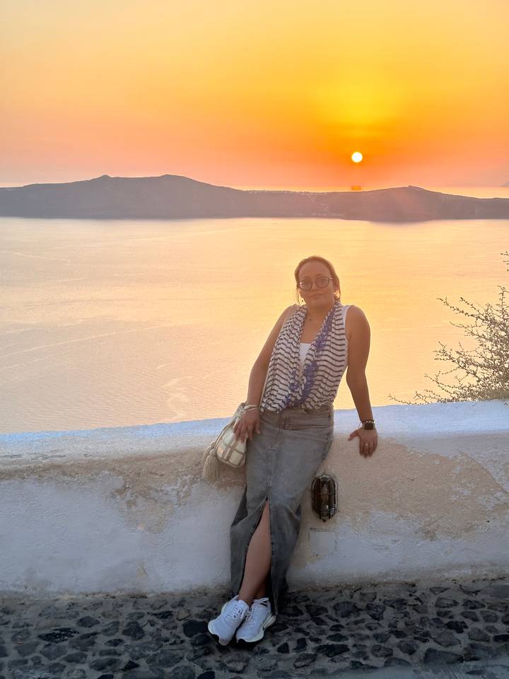 Personne posant devant un coucher de soleil sur l'eau.