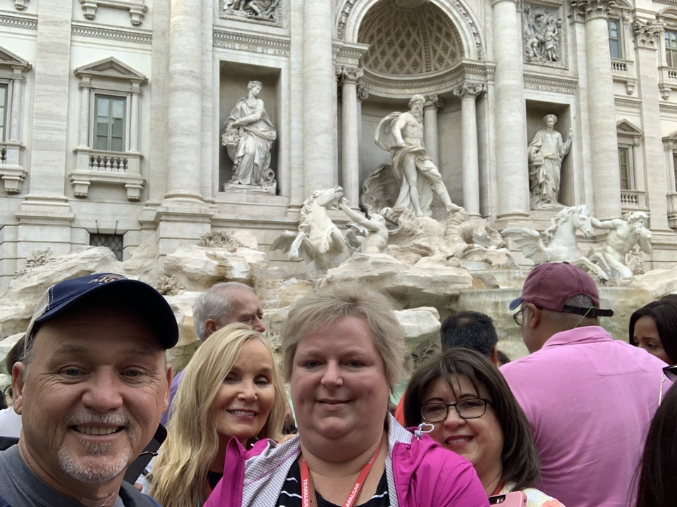 Groupe de personnes devant une fontaine célèbre.