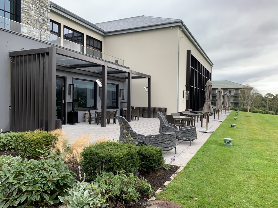 Terrasse d'hôtel avec sièges extérieurs et pelouse verte.