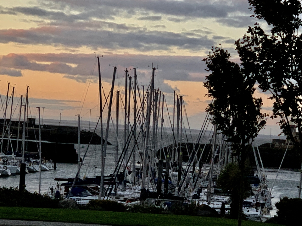 Bateaux dans une marina avec un coucher de soleil en arrière-plan.