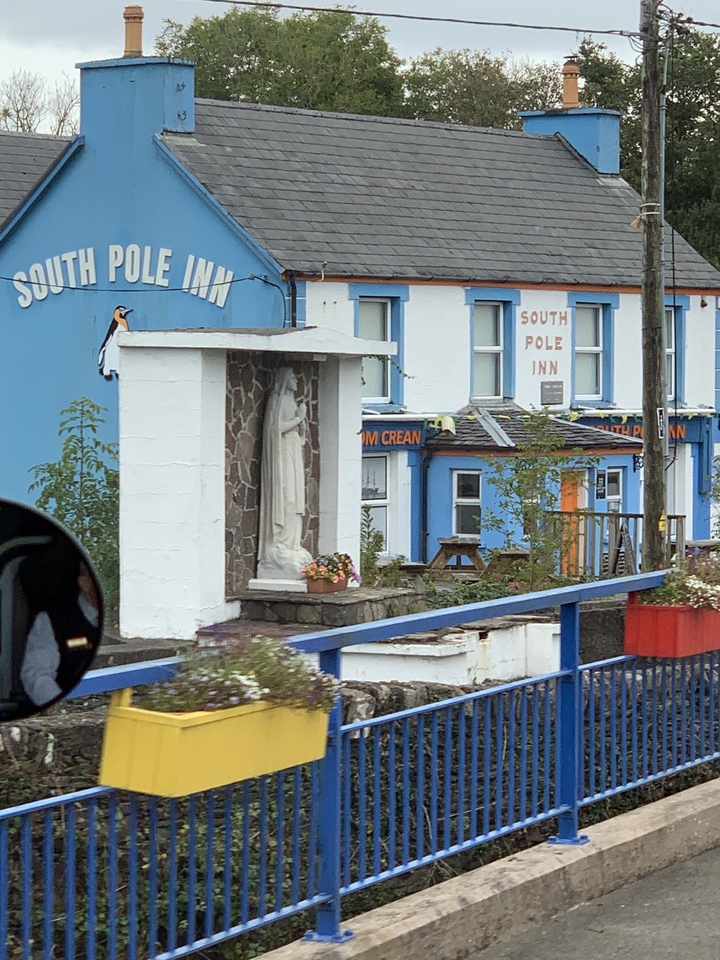 Auberge colorée avec une statue religieuse devant.