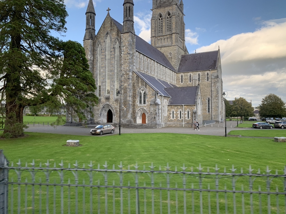 Grande église en pierre avec une voiture garée à l'extérieur.