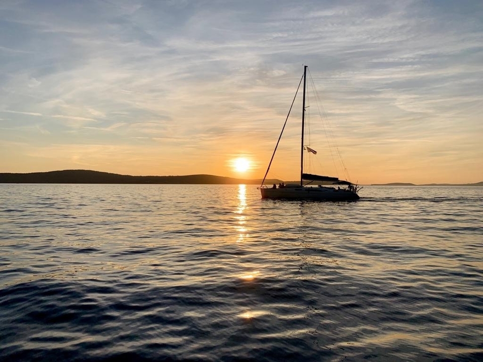 Silhouette de voilier contre le coucher de soleil sur l'océan.