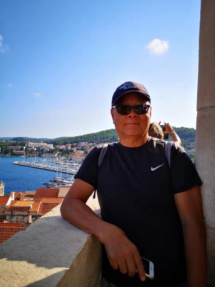 Homme posant avec une vue sur le port de plaisance depuis une hauteur.