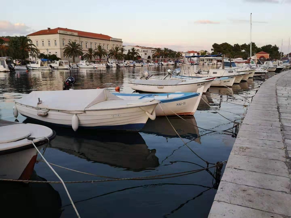 Petits bateaux amarrés dans un port avec des bâtiments en arrière-plan.