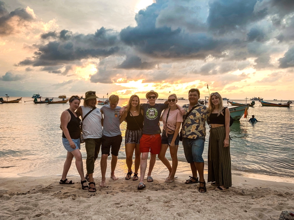 Group of friends posing on the beach at sunset.