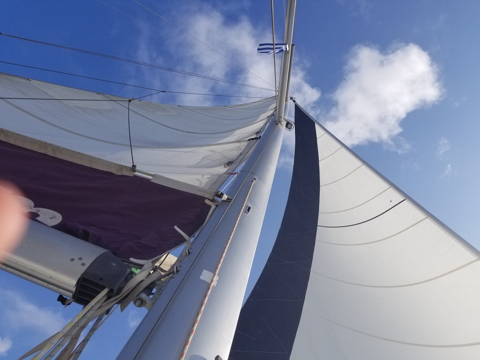 Mât et voiles de voilier contre un ciel bleu.