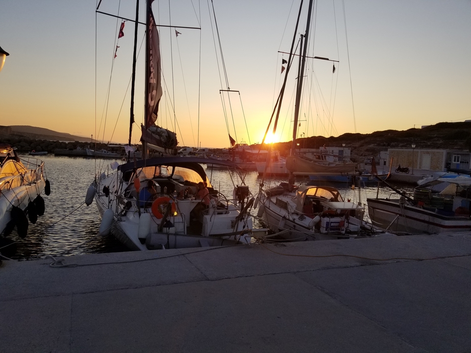 Voiliers amarrés dans un port au coucher du soleil.