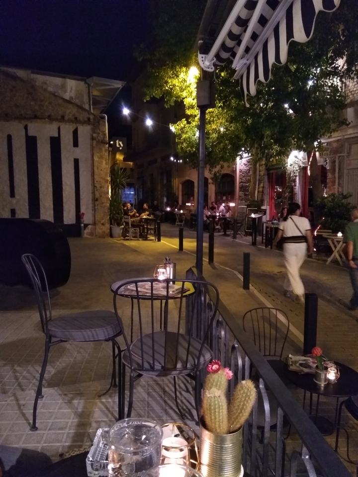 Vue de rue le soir avec des gens qui dînent en plein air.