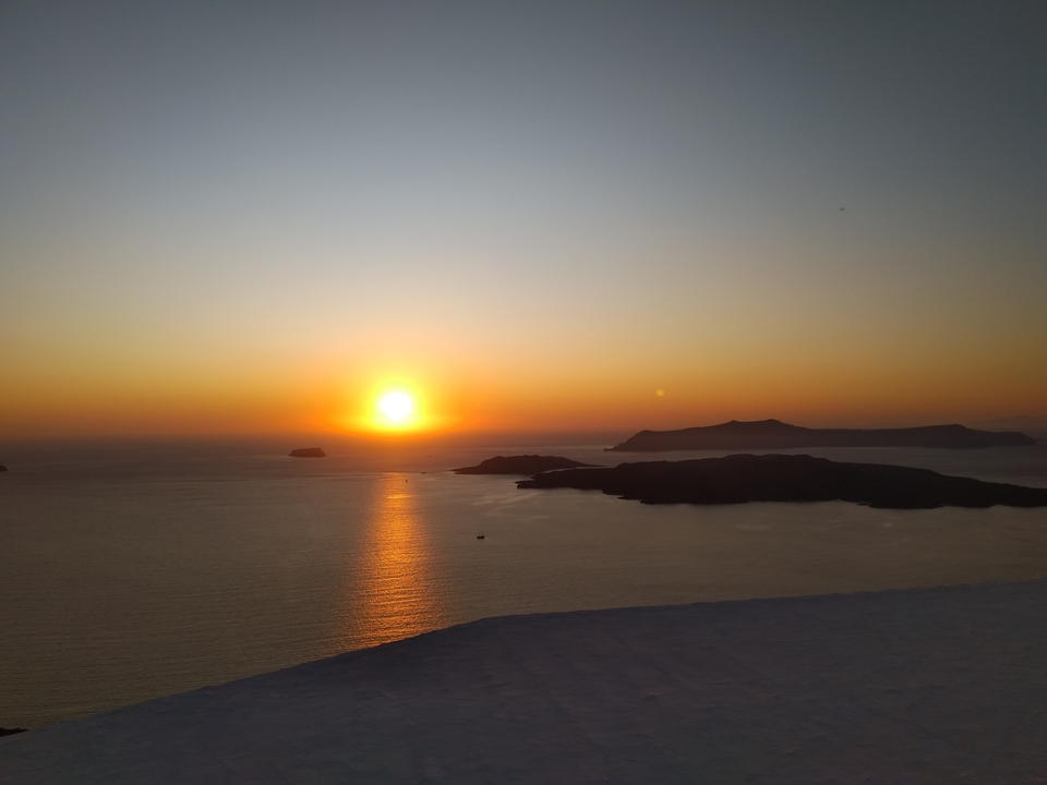 Vue du coucher de soleil sur la mer avec des îles au loin.