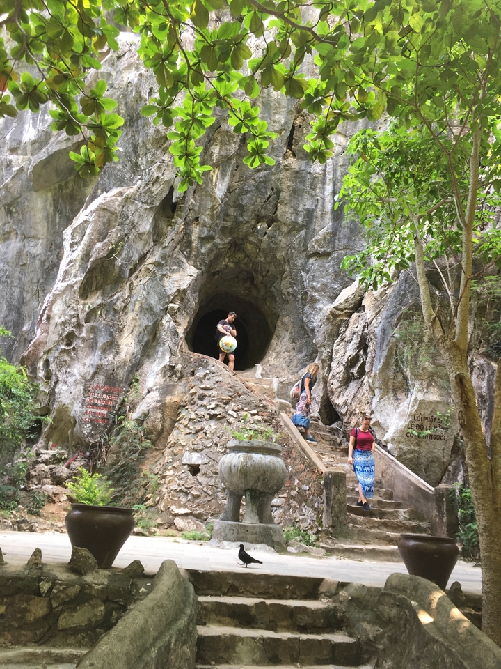 Personnes explorant l'entrée d'une grotte dans une zone rocheuse