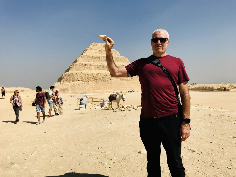 Une personne tenant la pointe d'une pyramide avec sa main dans un cliché d'illusion d'optique.